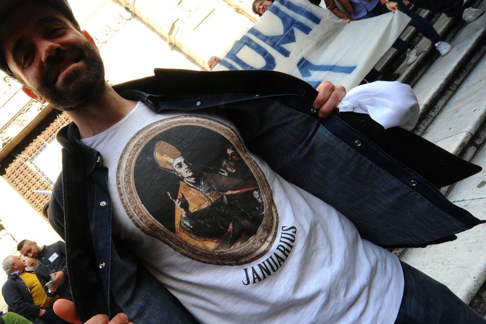 A man shows off his t-shirt depicting San Gennaro outside the cathedral in Naples, 5 March