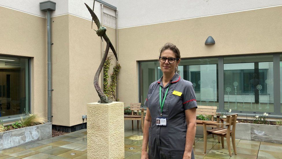 Dyson Cancer Centre - Ros Helps photographed outside on a patio area near a metal sculpture