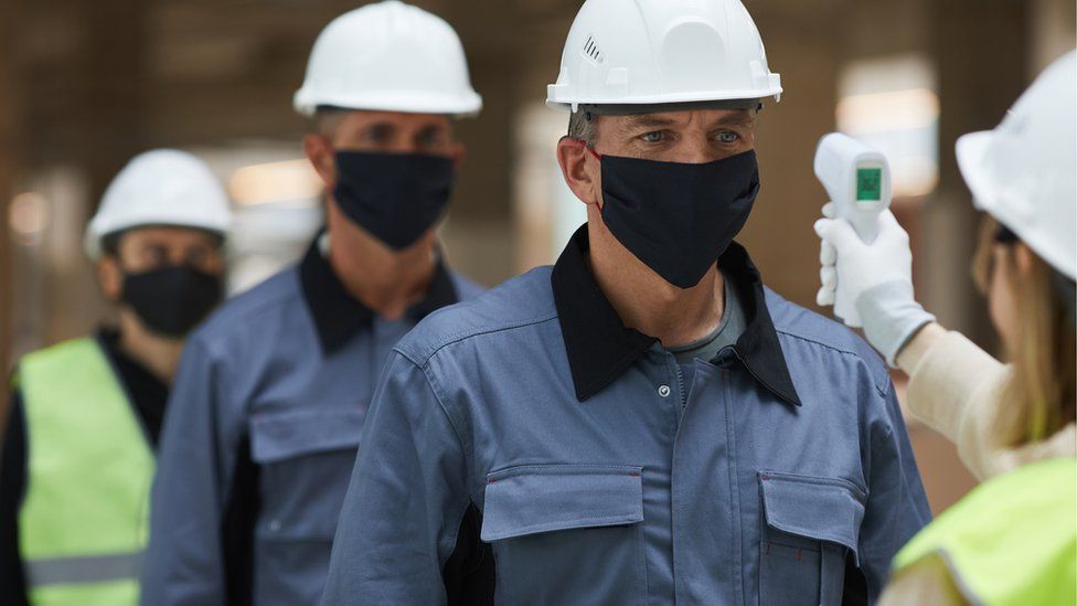 Construction workers having temperatures checked