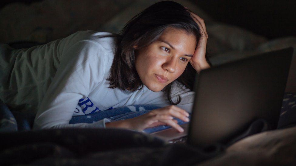 A woman looking at a computer in bed