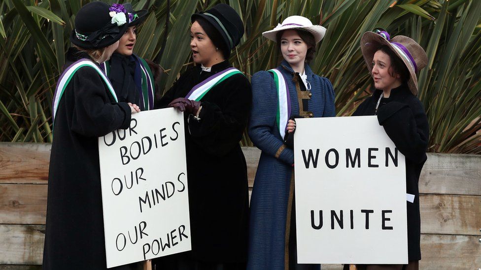 Students marking the anniversary by recreating a suffragette protest march