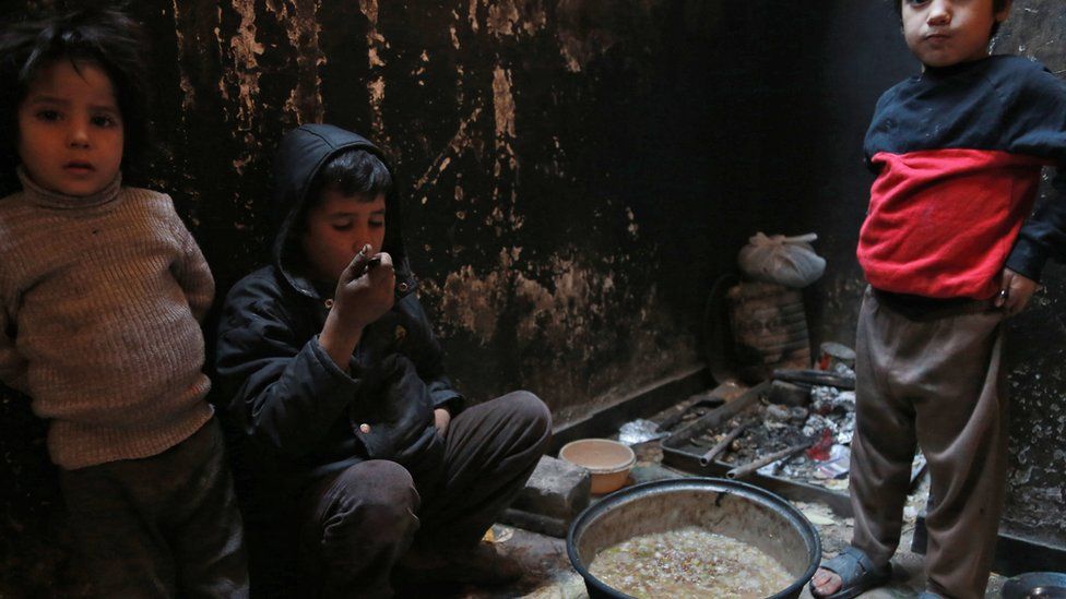 Children from the family of Umm Saeed wait to be served a meal of corn and cabbage on 6 November 2017 in Saqba, in the besieged rebel-held Eastern Ghouta, Syria