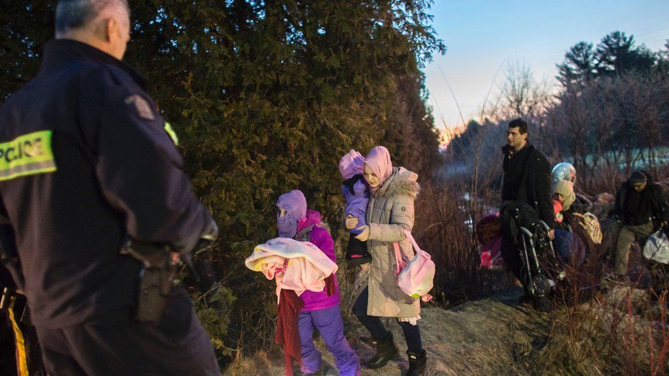 RCMP officers look on as an extended family of seven people from Turkey illegally cross the US-Canada border just before dawn on February 28, 2017 near Hemmingford, Quebec.