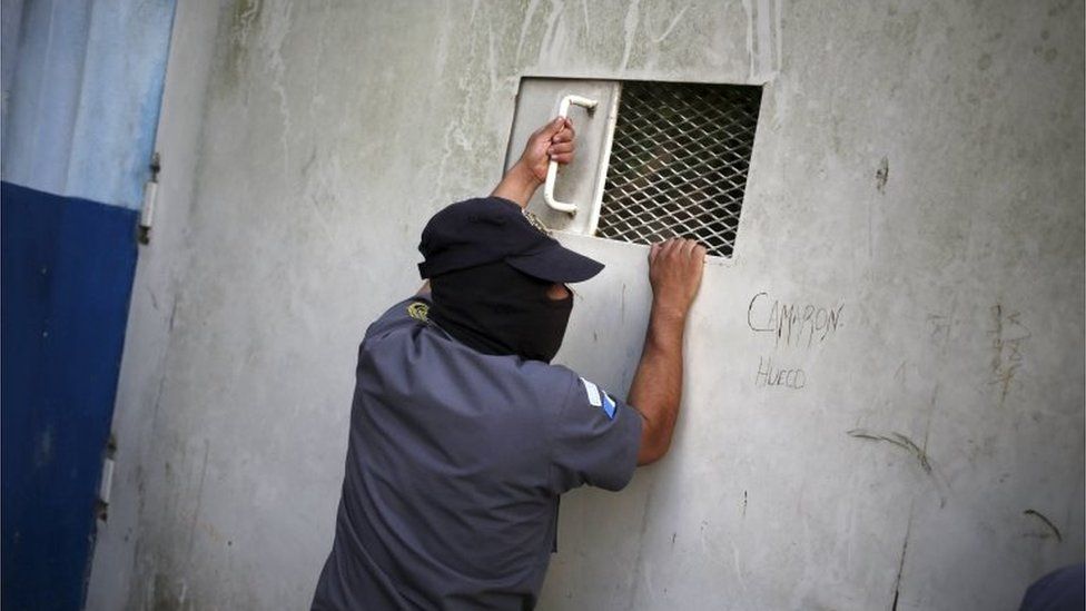 A penitentiary guard prepares to look through a window in a prison Guatemala City on 10 September, 2015.