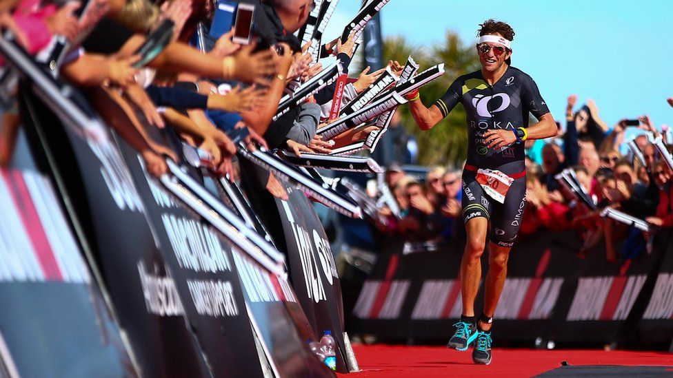 Jesse Thomas of the United States celebrates as he crosses the line to win Ironman Wales 2015