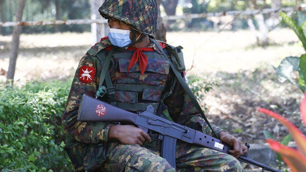 A Tatmadaw soldier sits holding a rifle