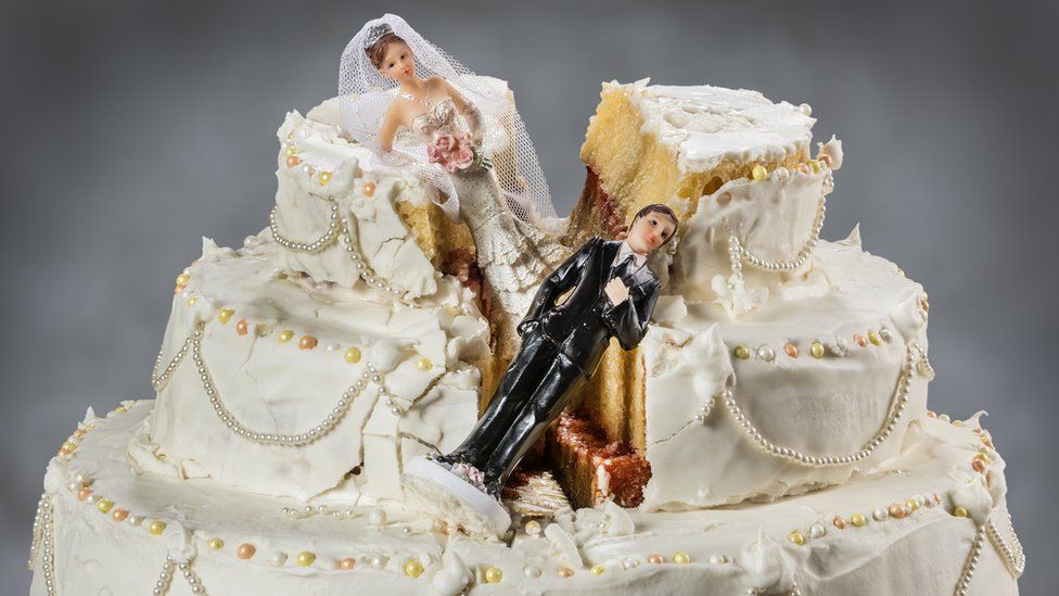Collapsed bride and groom figures on a wedding cake