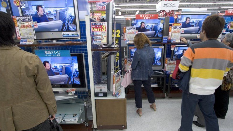 Shoppers look at televisions in Tokyo