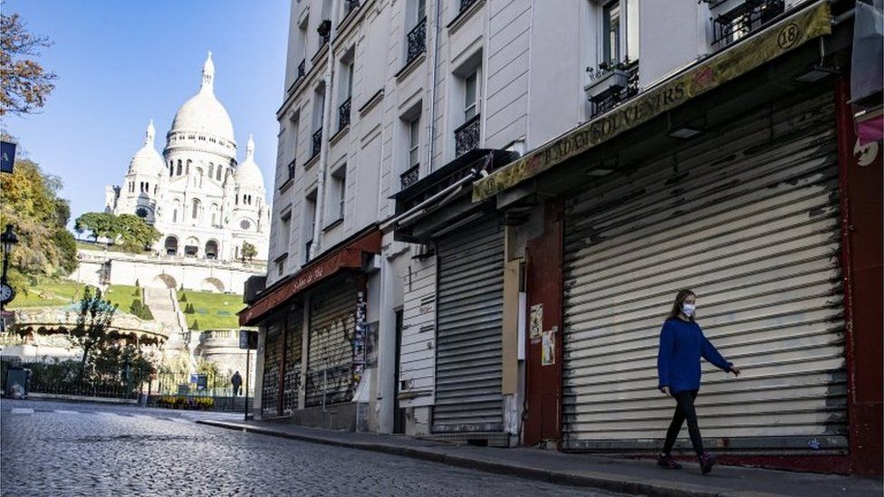 A woman walks on an empty street in Paris