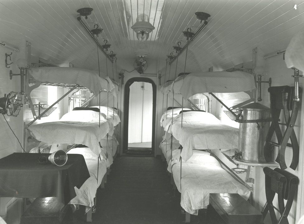 Black and white photo of several beds inside a hospital train