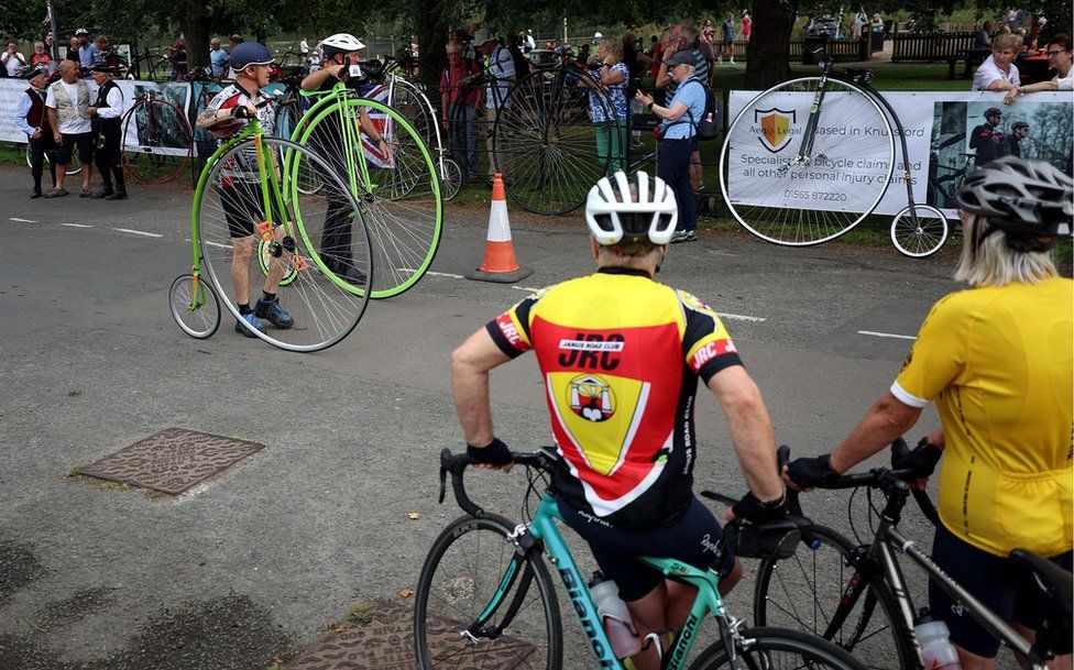 cyclists watch penny farthing riders prepare