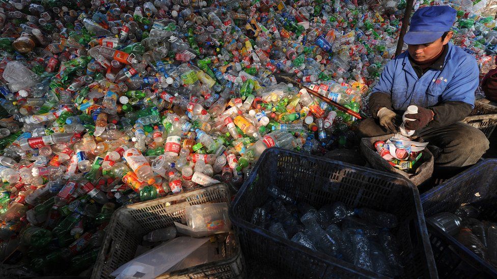 A worker sorts through various plastic bottles collected at a recycling collection centre in Hefei, east China's Anhui province