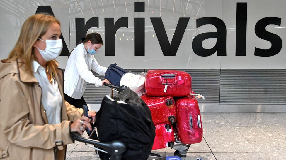 Passengers push their luggage trolleys on arrival in Terminal 5 at Heathrow airport in London in June 2021