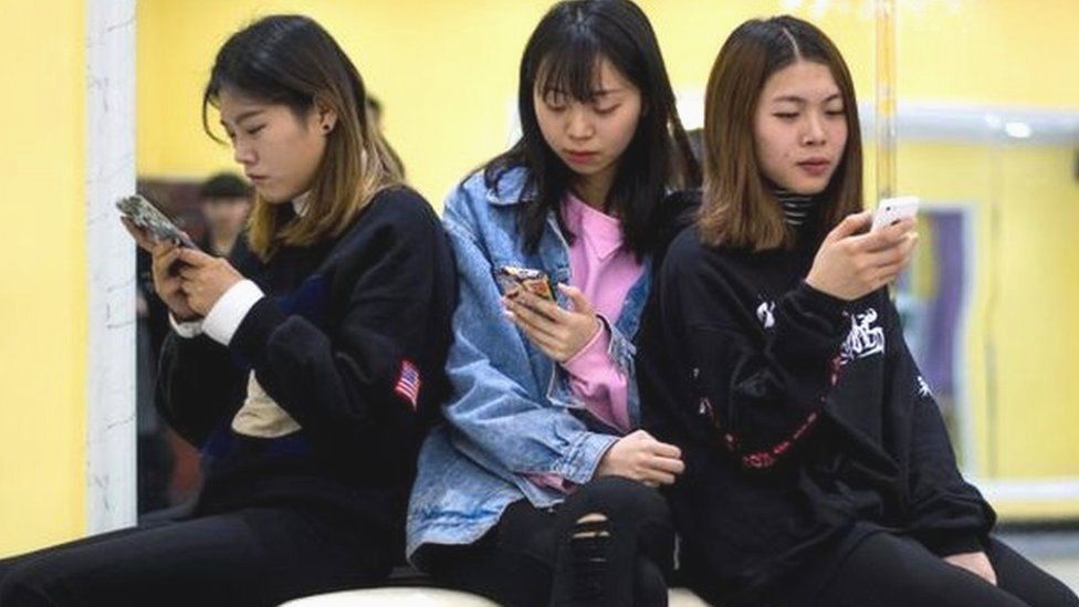 Teenaged girls playing with their phones in Yiwu, Zhejiang Province