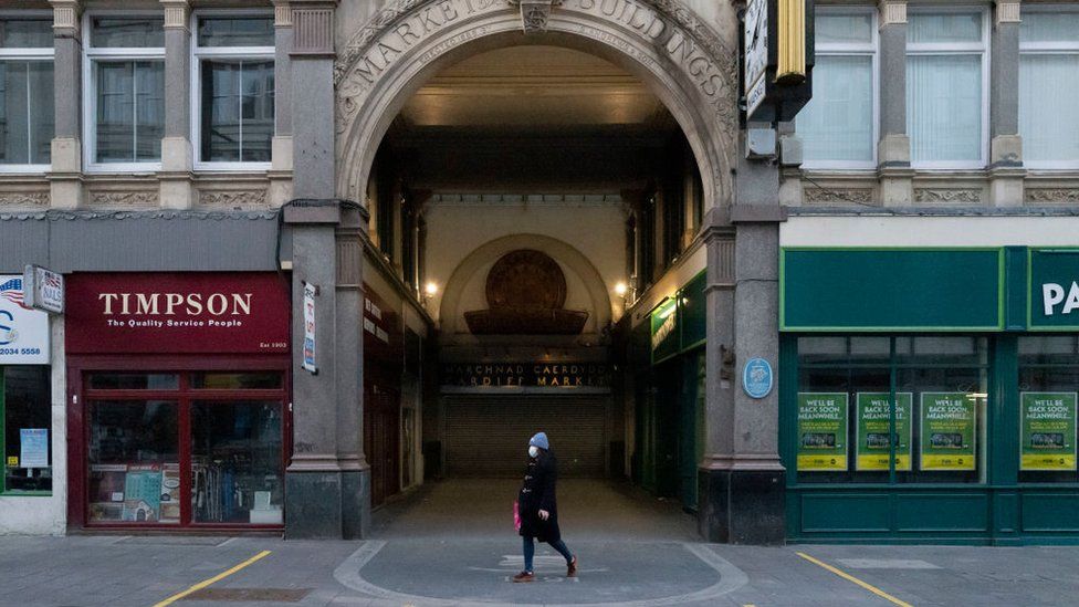 A lone woman walking past shut shops in Cardiff city centre