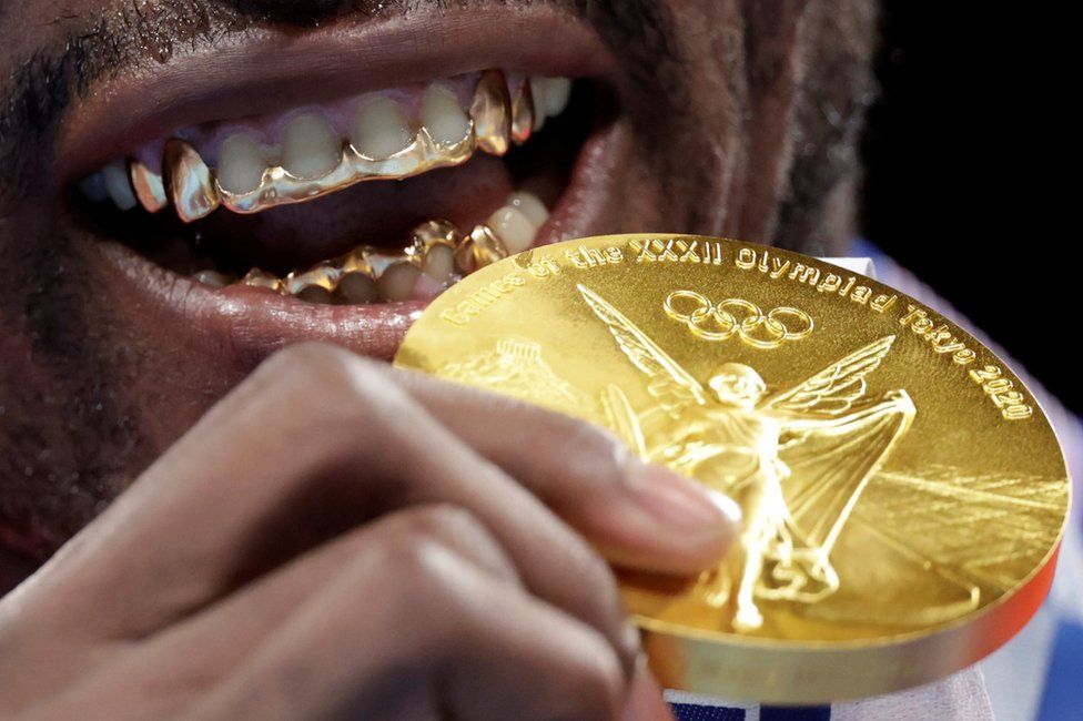 Tokyo 2020 Olympics gold medallist Julio Cesar La Cruz of Cuba holds his medal up to his mouth, which has gold on his teeth