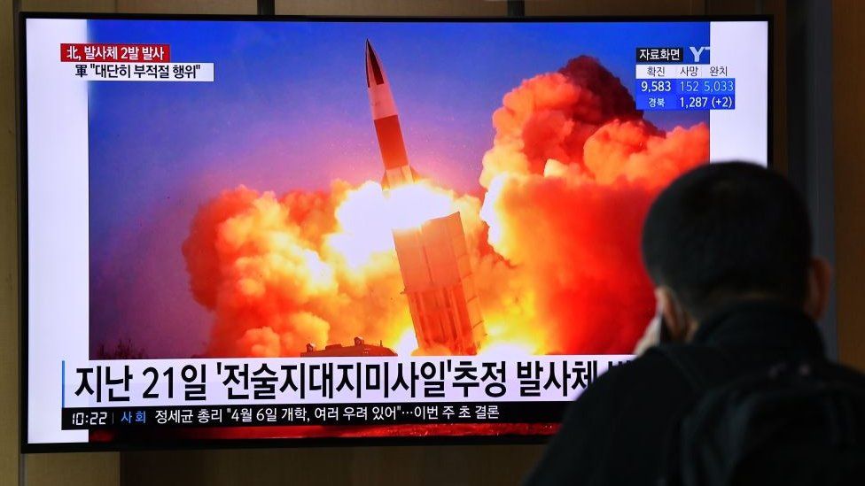 A man watches a news broadcast showing file footage of a North Korean missile test
