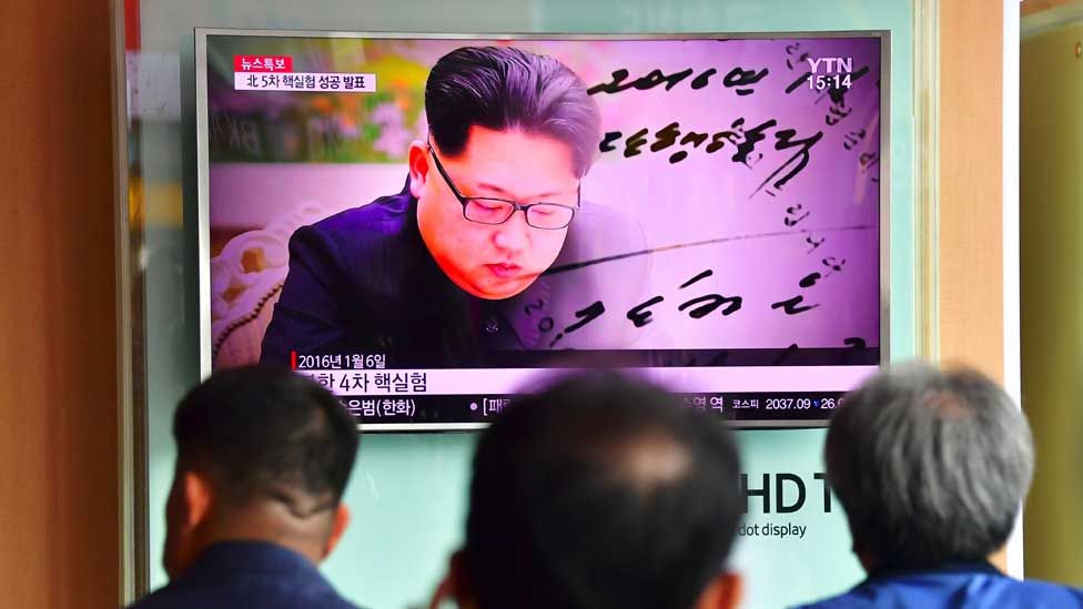 People watch a television news report, showing file footage of North Korean leader Kim Jong-Un, at a railway station in Seoul