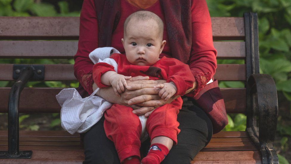A woman holds a baby at a local park on 12 May 2021 in Beijing, China