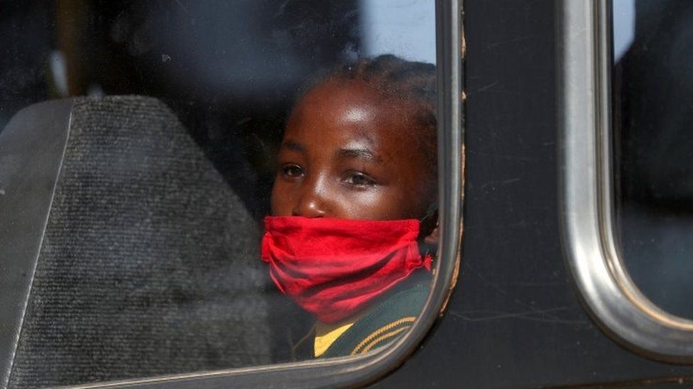A girl wearing a mask looks on through a bus window in Eikenhof, south of Johannesburg, South Africa. Photo: August 2020