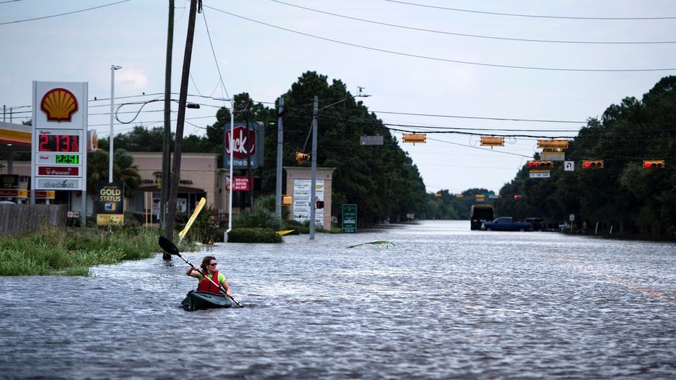 A woman paddles down a flooded road while shuttling deliveries for her neighbors during the aftermath of Hurricane Harvey on August 30, 2017 in Houston, Texas