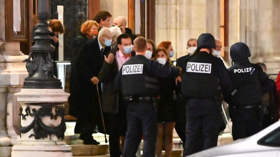 Opera guests leave the state opera under the supervision of armed policemen in central Vienna