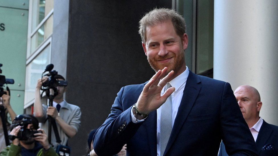 Prince Harry smiling and waving outside London's High Court.