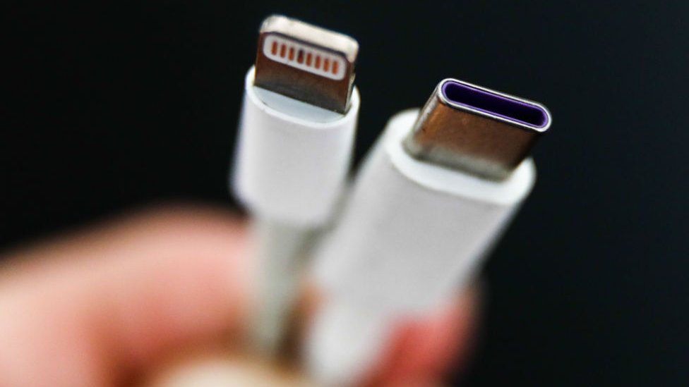 Зарядное устройство USB Type-C рядом с фирменным кабелем Lightning от Apple.