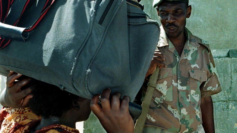 A South African soldier checks the passports of Zimbabwean citizens who walk across the Beit Bridge border post between the two countries to buy food 07 January 2003. More and more Zimbabweans are venturing across the border to buy basic foods such as fruits and Maize meal, which is not available in Zimbabwe.