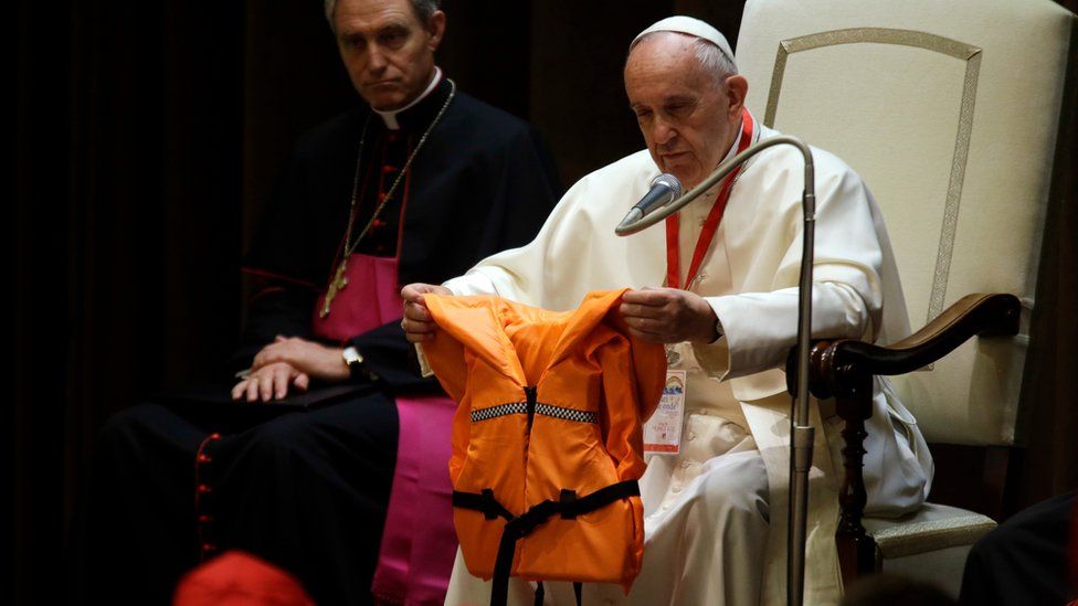 Pope Francis holds a life jacket which was donated to him by a migrants" rescuer during a meeting with some 400 children coming by train from the region of Calabria, at the Vatican
