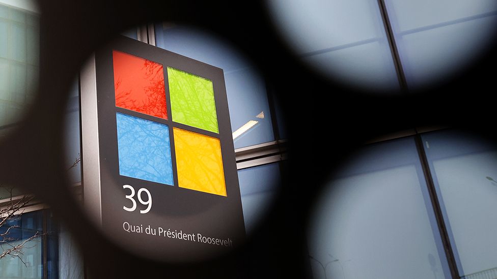 Логотип американской компании по производству компьютеров и персональных компьютеров Microsoft виден сквозь сетку ее штаб-квартиры 25 января 2023 года в Исси. -ле-Мулино, Франция