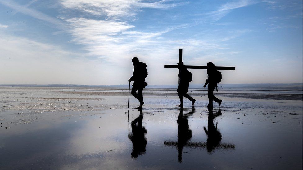 Pilgrims carry crosses along a beach to Holy Island