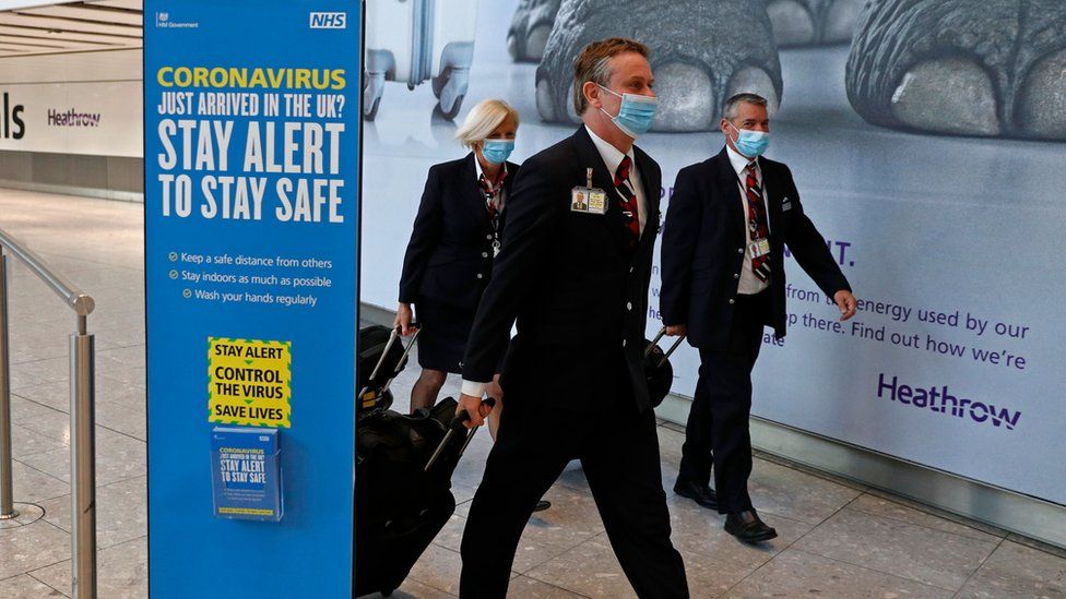 British Airways flight crew wear protective facemasks as they arrive at Terminal 5 at Heathrow airport