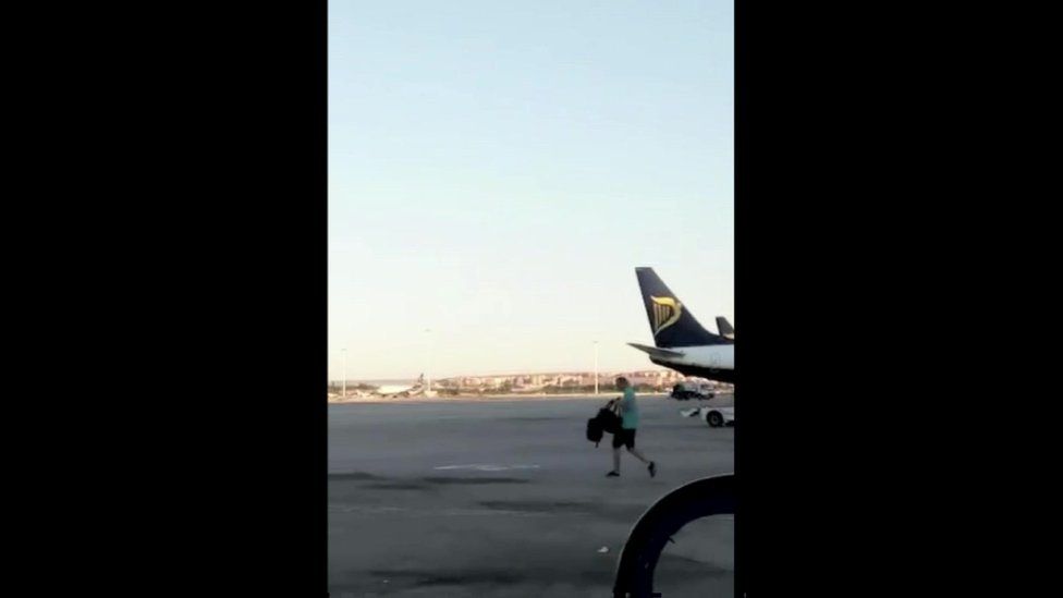Man walking past plane tail