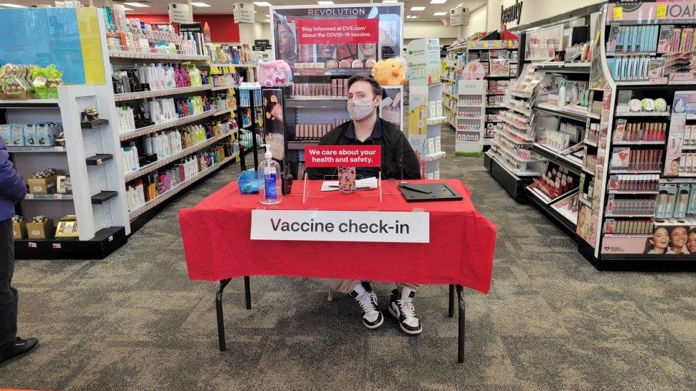 Мужчина сидит на стойке регистрации вакцины COVID в CVS в Принстоне