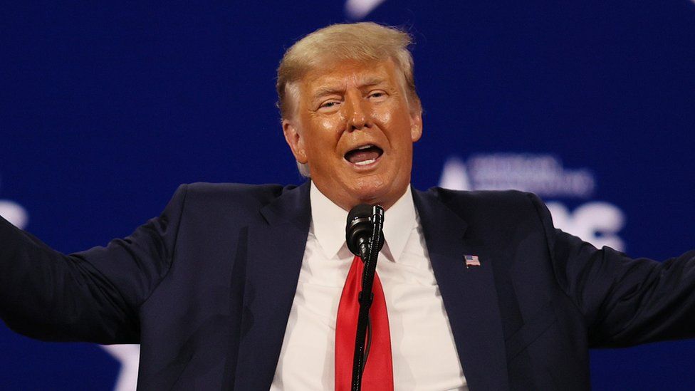 Former President Donald Trump gestures with open arms at a conference in February