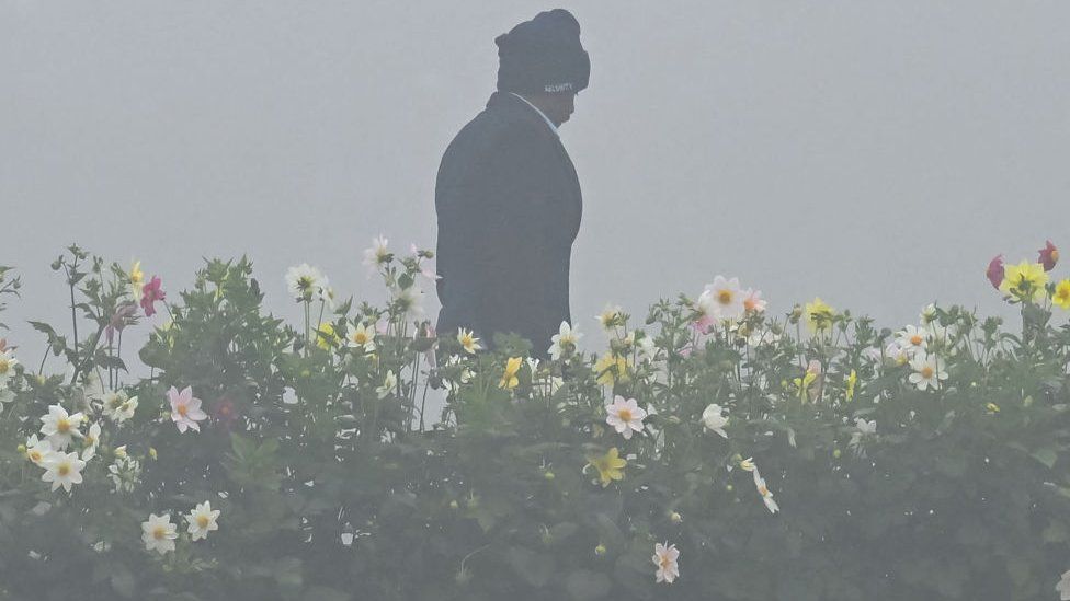 A security person walks through thick fog at Mahatma Gandhi memorial in Delhi on 30 January