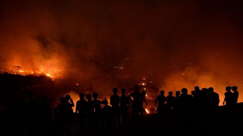 Bangladeshi onlookers gather after a fire blazes in a slum in Dhaka on August 16, 2019.