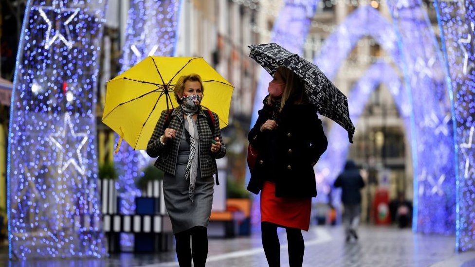 People walk past Christmas decorations in central London