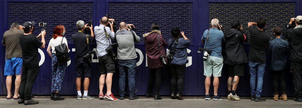 Photographers and videographers peer into a car park trying to get a glimpse of Serbian tennis player Novak Djokovic at the offices of his legal team