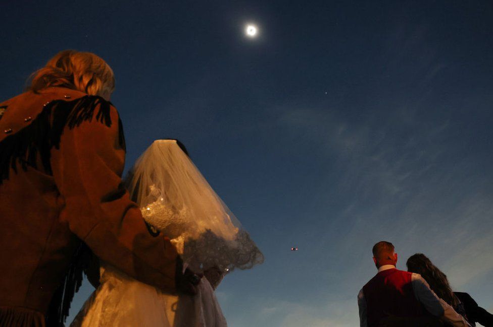 Couples view the solar eclipse during totality at a mass wedding at the Total Eclipse of the Heart festival on April 8, 2024 in Russellville, Arkansas.