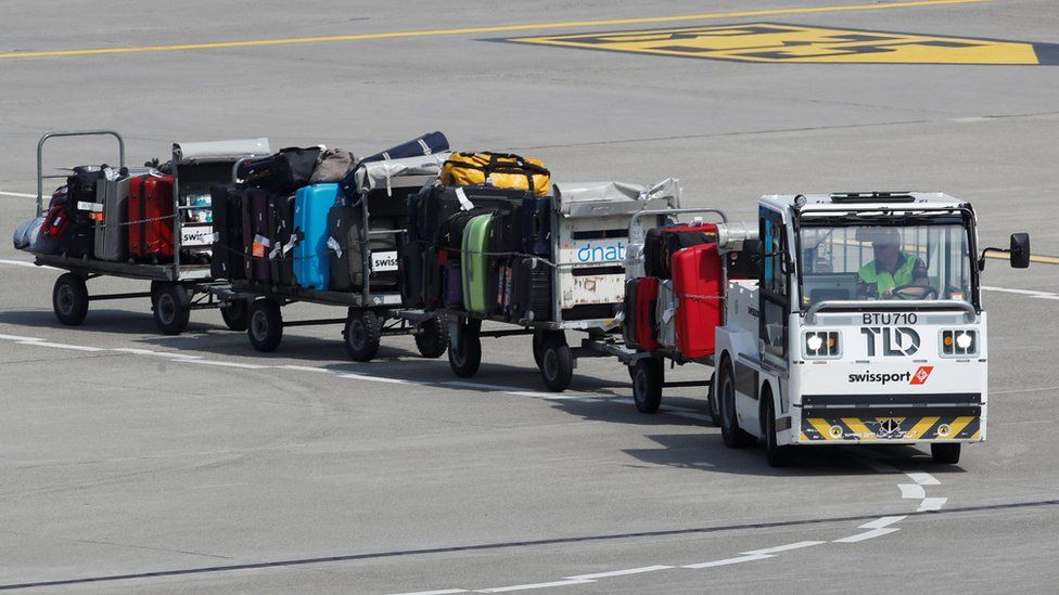 Truck pulling luggage trailers on airport runway