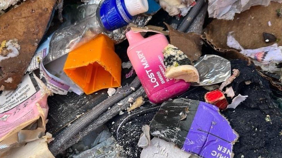 Disposable vapes are seen amid the rubbish on the road