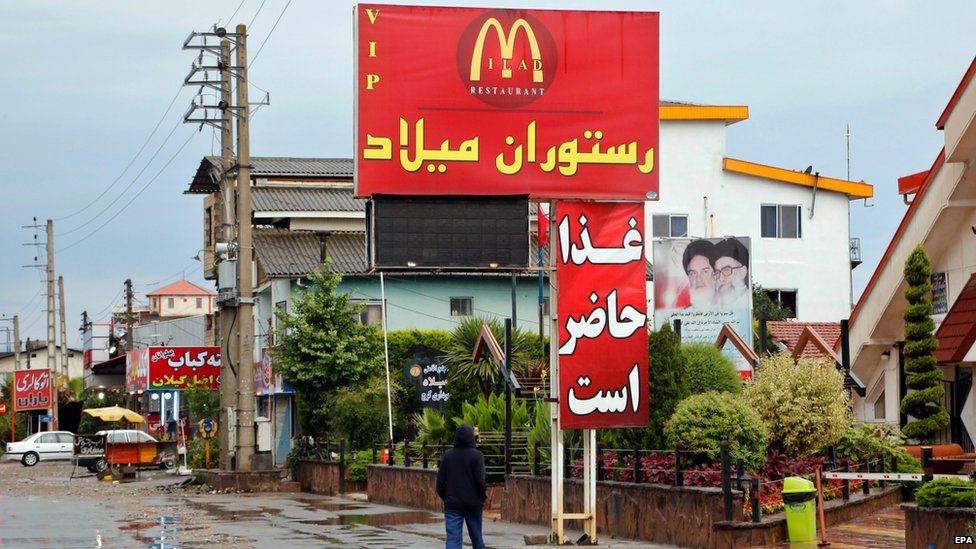 A man walks past the sign of the restaurant Milad bearing a McDonald's logo in the city of Tone-Kabon, Mazandaran province, northern Iran (20 July 2015)