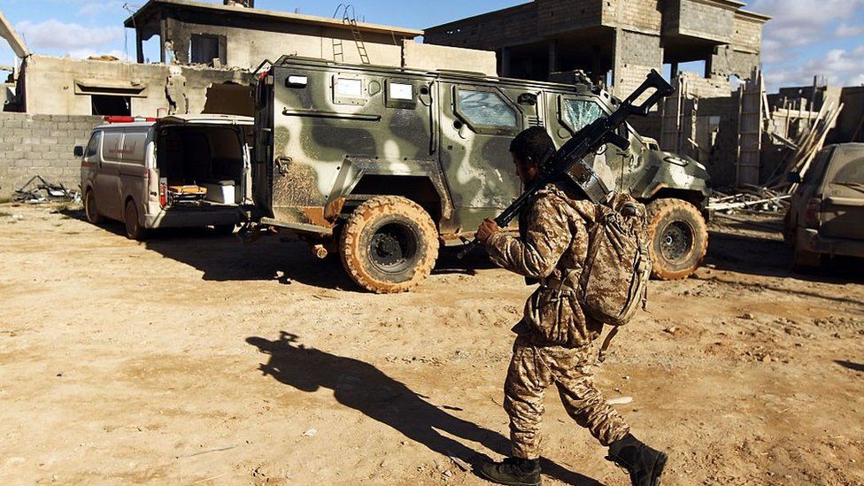 A member of the Libyan National Army (LNA) walks past an armoured vehicle as he holds a position during fighting against jihadists in Qanfudah, on the southern outskirts of Benghazi,