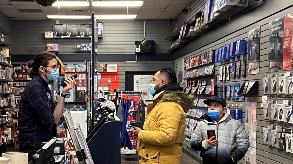 Сотрудник разговаривает с покупателем в магазине GameStop в Нью-Йорке, штат Нью-Йорк, США, 30 января 2021 г.