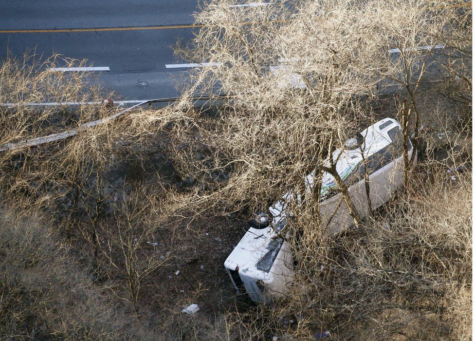 A bus lies after it veered off to the opposite lane on a mountain road in Karuizawa, Nagano prefecture