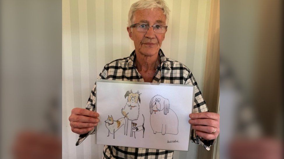 Paul O'Grady holding portrait of his dogs