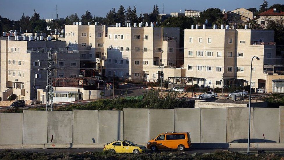 Cars drive on a road used by Palestinians from the Jalazone refugee camp past a defensive wall that surrounds the Israeli settlement of Beit El (7 April 2015)