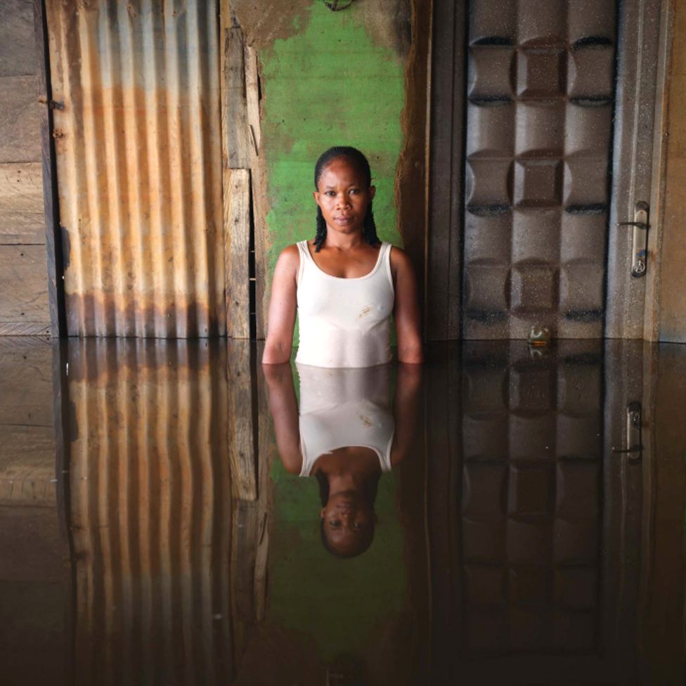 Джанет Эке стоит в паводковой воде в своем доме в муниципалитете Огбия, штат Байелса, Нигерия, ноябрь 2022 г.